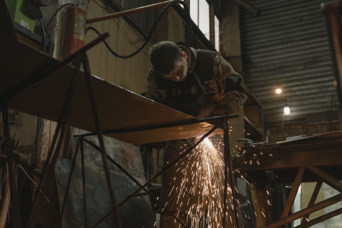 A welder in protective gear at work, sparks flying