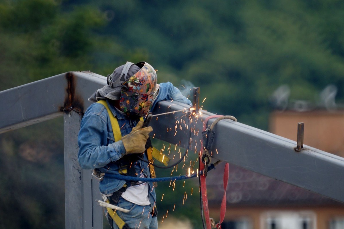 A welder working outdoors on a steel structure