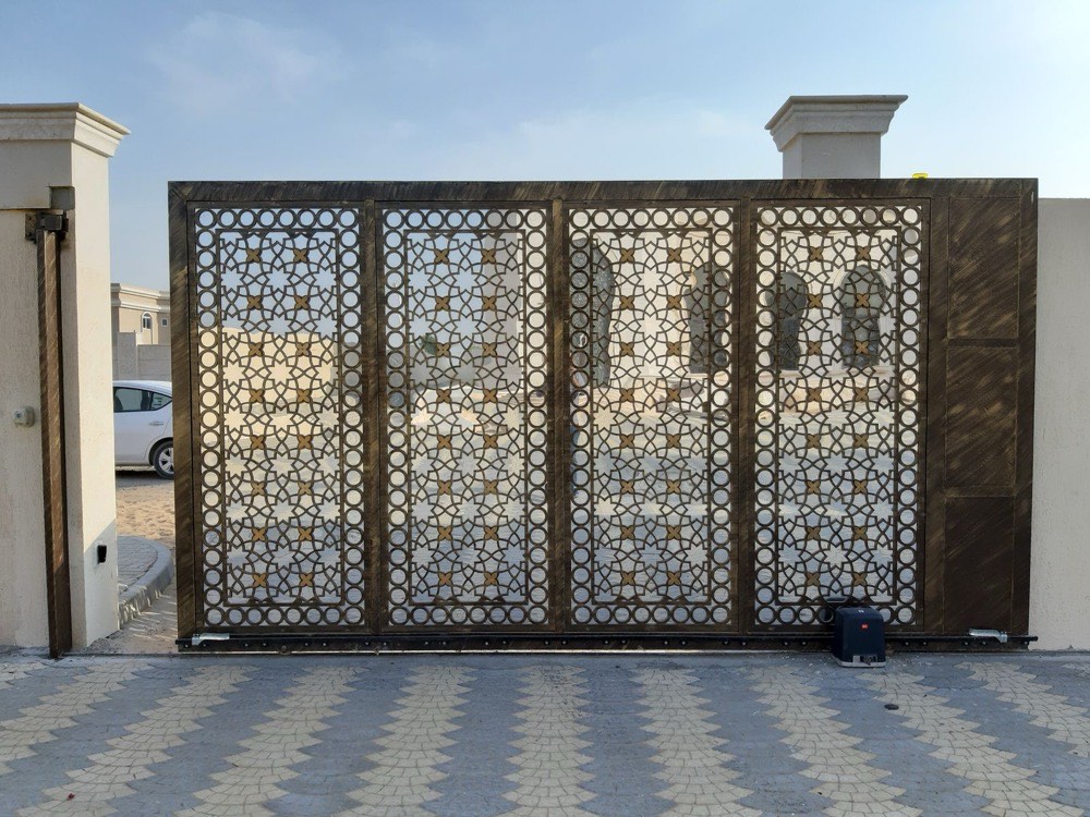 A decorative metal driveway gate with a laser-cut pattern