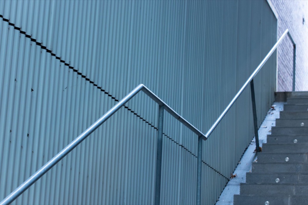 A galvanized steel handrail on an exterior staircase